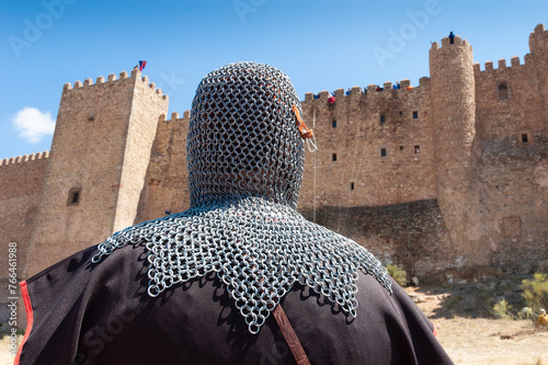 Un caballero medieval con cota de malla observa el asalto a las murallas del castillo durante un festival medieval. photo