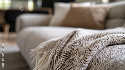 Minimalist elegance: beige knitted throw for modern sofa, bright living space. Cozy interior detail