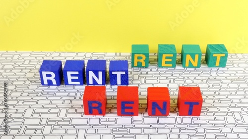 Single word RENT on wooden block, house rent taxes concept.