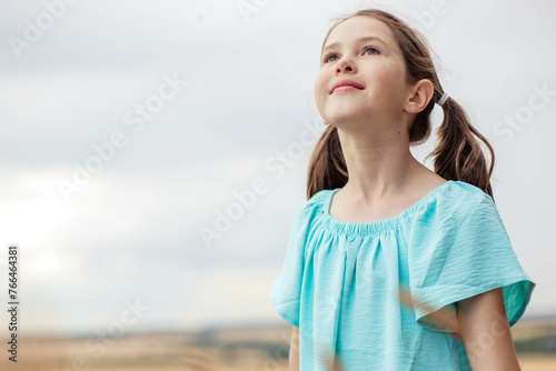 Portrait of adorable girl looking up against sky background