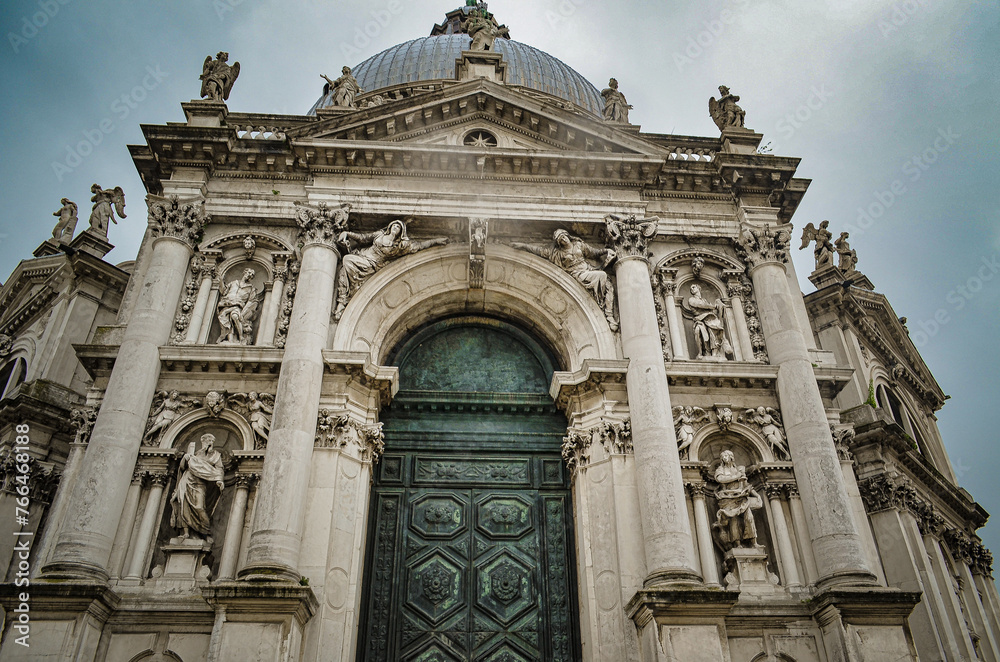 Minor basilica in the Baroque style, with Corinthian and Ionic sculptures, green massive door in perspective, bottom view