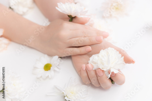 Stylish trendy nail young woman hands pink manicure on white background with flowers  banner cosmetic and beauty care