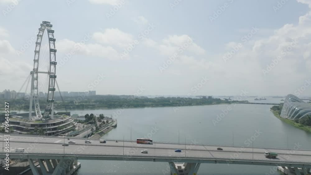 Drone of the traffic on Benjamin Shearse Bridge over a river with Singapore Flyers in the background