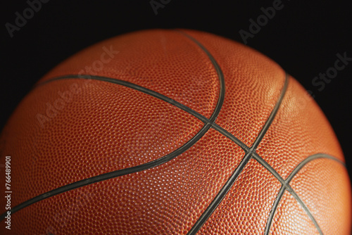 Orange basketball in the light on a black background, sports background