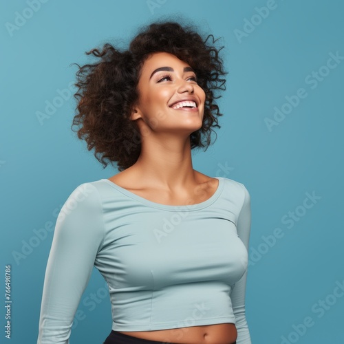 Laughing woman with curly hair wearing blue long sleeved crop top
