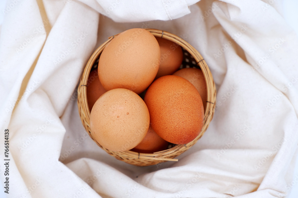 Eggs in a basket with calico fabric. Brown eggs in the wicker basket for healthy food, ingredient, and rustic kitchen concepts. Using basket and eco-friendly fabric. Egg top view for food photography. Eggs in a basket with calico fabric. Brown eggs in the wicker basket for healthy food, ingredient, and rustic kitchen concepts. Using basket and eco-friendly fabric. Egg top view for food photography.
