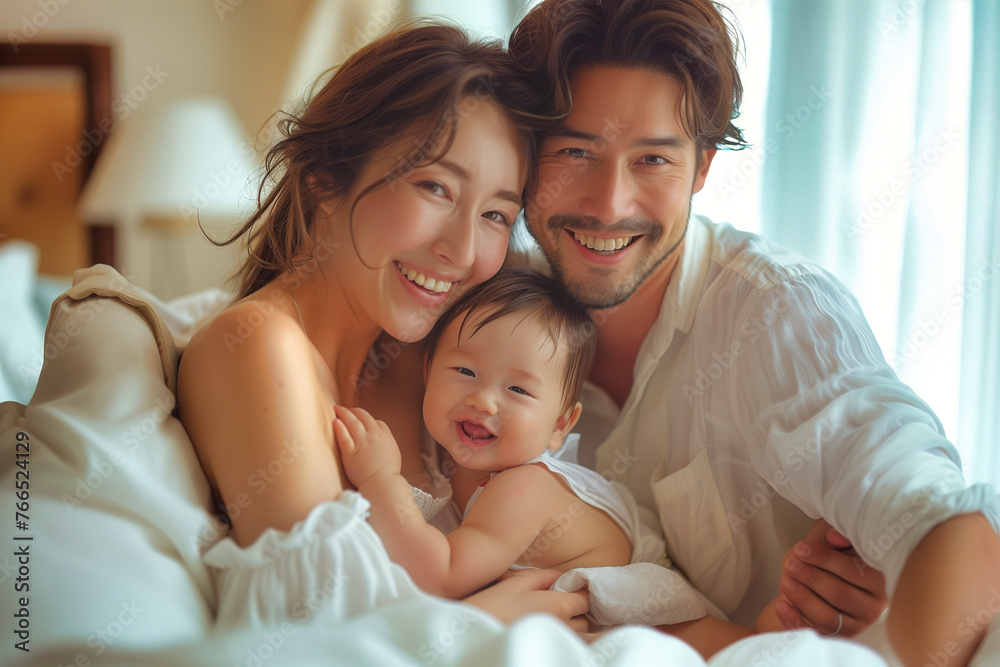  An asian couple with their months-old baby cuddling on the sofa at home