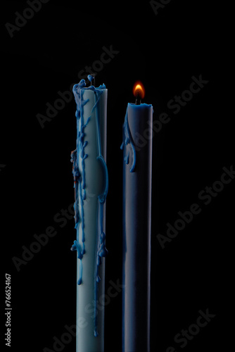 Blue candles covered in melted wax on black background