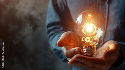 Human hands holding a glowing light bulb with gears inside, illustrating the connection between human intellect and mechanized business processes #766525523