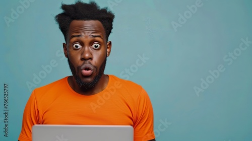 Shocked African woman while watching in on laptop isolated blue background .Image of excited screaming young woman sitting isolated over blue background. Looking camera.Portrait African American man