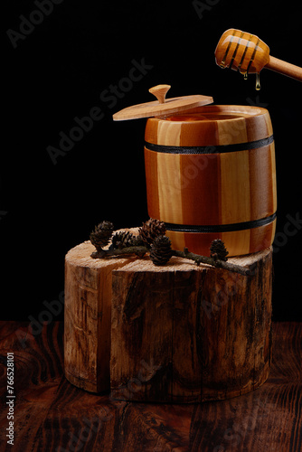 Barrel of liquid  honey with wooden spoon on rustic stump