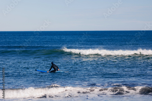 Man with surfboard in wetsuit going to surf in winter ocean Kamchatka Russia