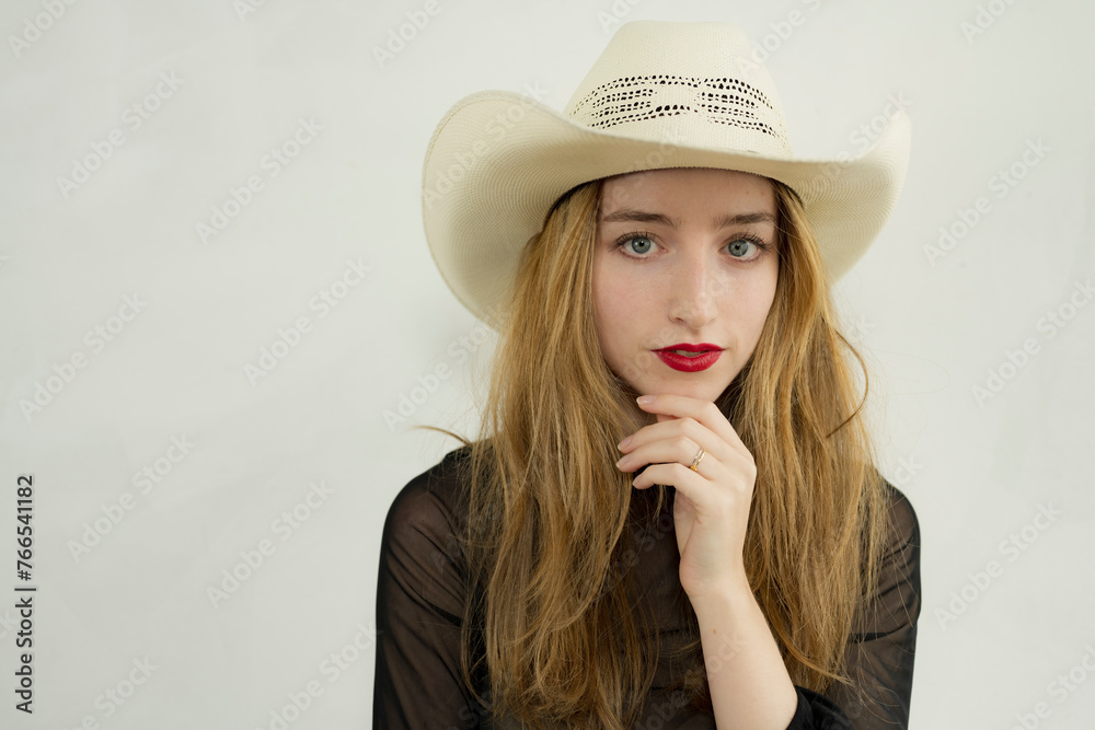Pretty young woman in white jeans, lacy black top and cowboy poses in a studio setting. Pretty young woman in white jeans, lacy black top and cowboy poses in a studio setting.