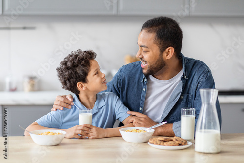 Happy african american father and son have breakfast together