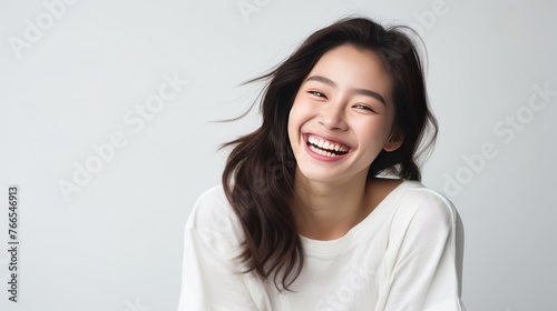 A woman with long hair and a white shirt is smiling