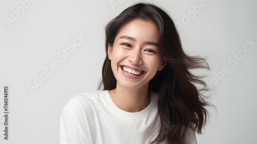 A woman with long hair and a white shirt is smiling