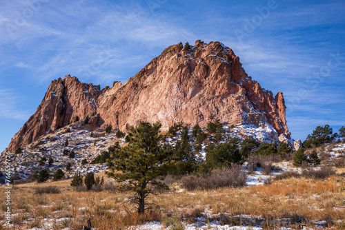 Garden of the Gods in Colorado Springs.  Red rock and blue sky. Tall red stone formations with light snow.  Natural red rock formations in Colorado winter.  Trees and desert scrub with snow foreground photo