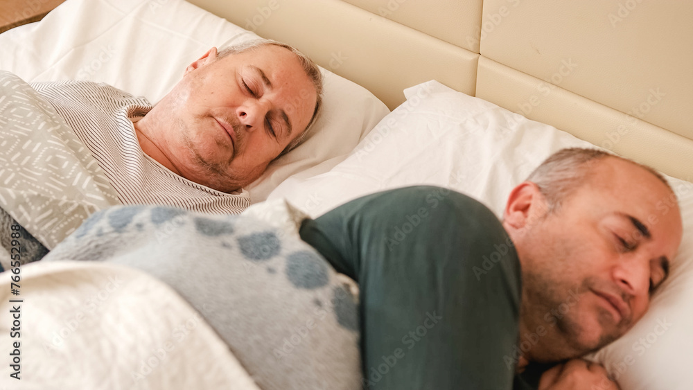 Mature gay couple waking up in bed in the morning Mature gay couple waking up in bed in the morning