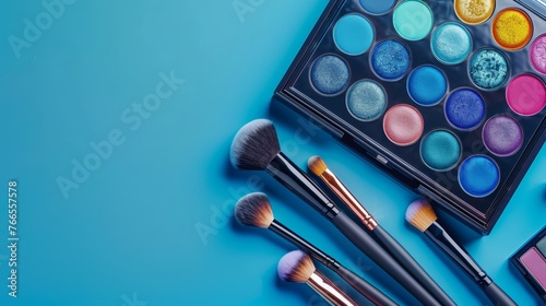 Makeup eyeshadow palette with vibrant colors and professional brushes on a blue background. Flat lay composition with copy space. Beauty and cosmetics concept photo