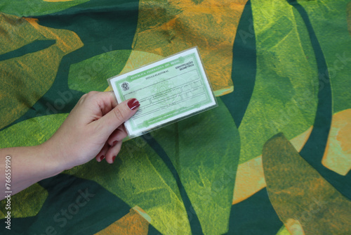 Brazil voter registration card in a woman’s hand isolated in a abstract green background 