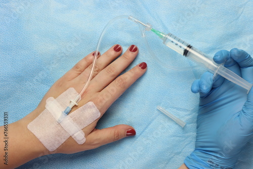 Syringe with drug connected with a peripheral catheter access in a woman’s hand 