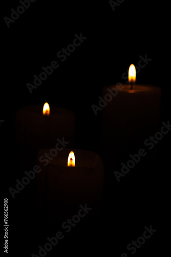 Candles  beautiful candles positioned on dark surface  black background  selective focus.