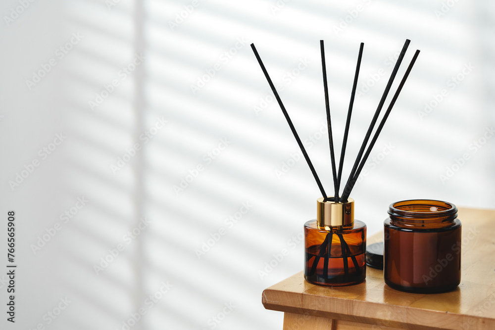 Aromatherapy Reed Diffuser and Scented Candle on a Wooden Table in a Cozy Room Aromatherapy Reed Diffuser and Scented Candle on a Wooden Table in a Cozy Room