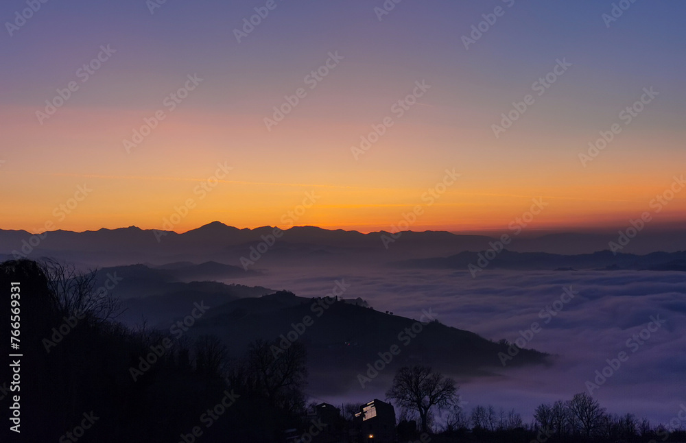 Un mare di nuvole bianche  e di nebbia riempie le valli sotto le montagneal tramonto  - obrazy, fototapety, plakaty 