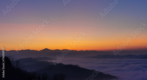 Un mare di nuvole bianche  e di nebbia riempie le valli sotto le montagneal tramonto  © GjGj