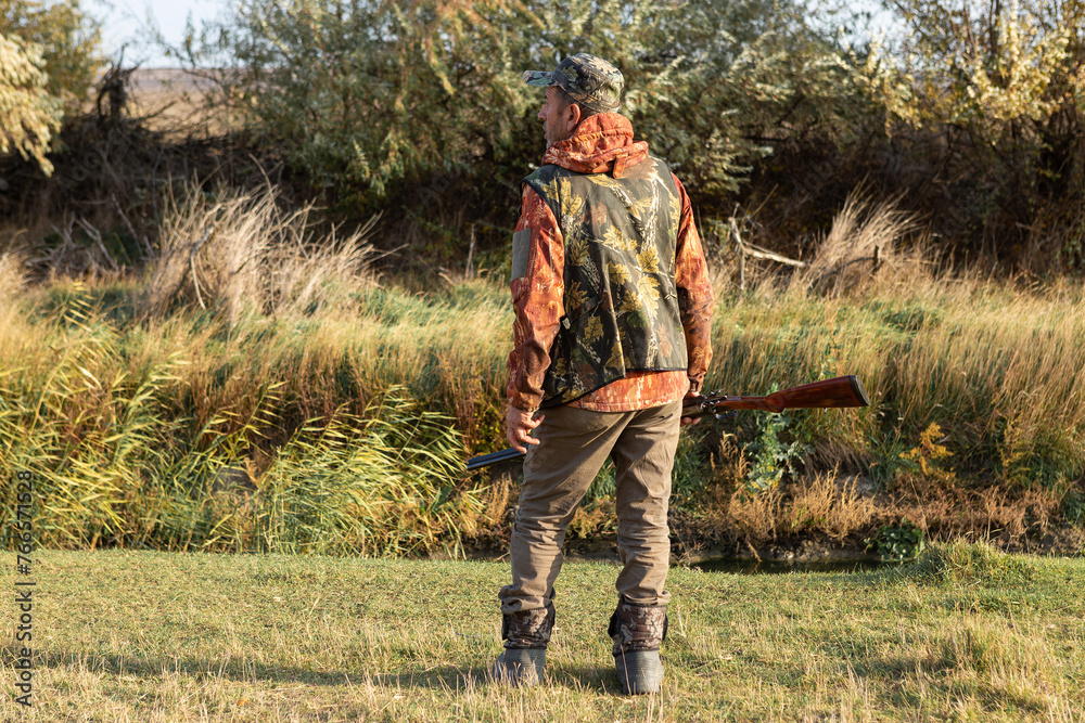 Mature man hunter with gun while walking on field. Mature man hunter with gun while walking on field.