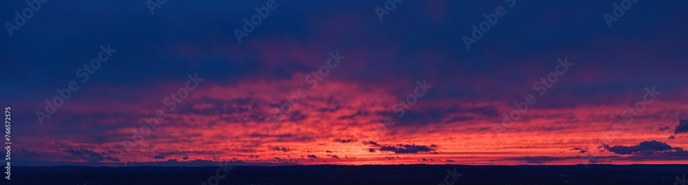 Ideal for sky replacement projects: panoramic aerial shot of a  red and orange illuminated clouds of dark blue evening sky just after sunset.