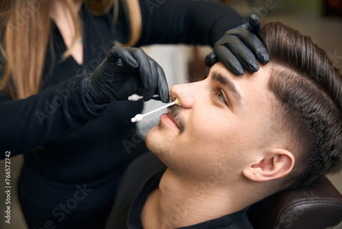 Master barber doing depilation beauty procedure in barbershop