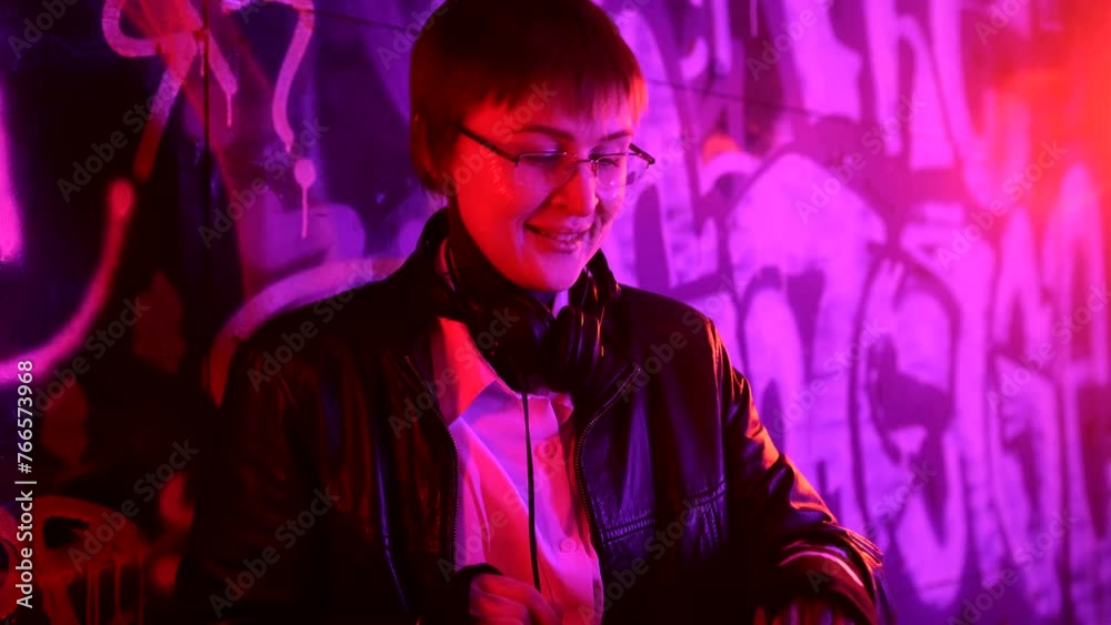 Young Caucasian female dj standing by mixer console creating music and dancing at the party in night club