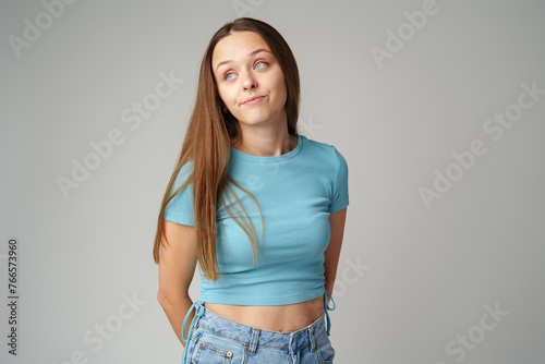 Thinking young lady standing over gray background