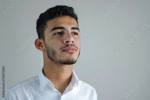 A man with a beard and a white shirt is looking at the camera