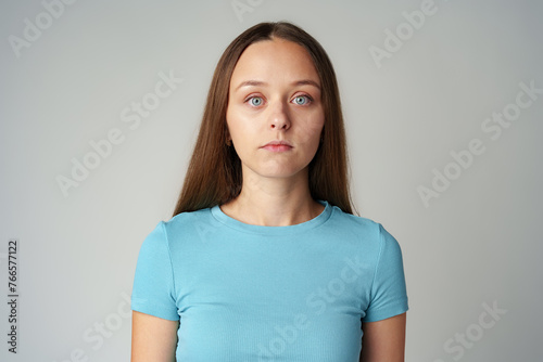 Young woman in blue t-shirt looking at camera with serious expression
