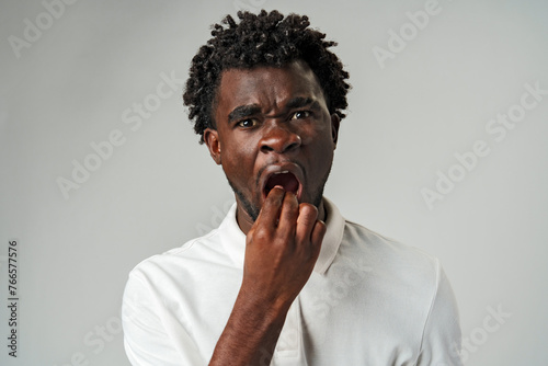 Young Man With Curly Hair Feels Tooth Pain Against a Gray Background