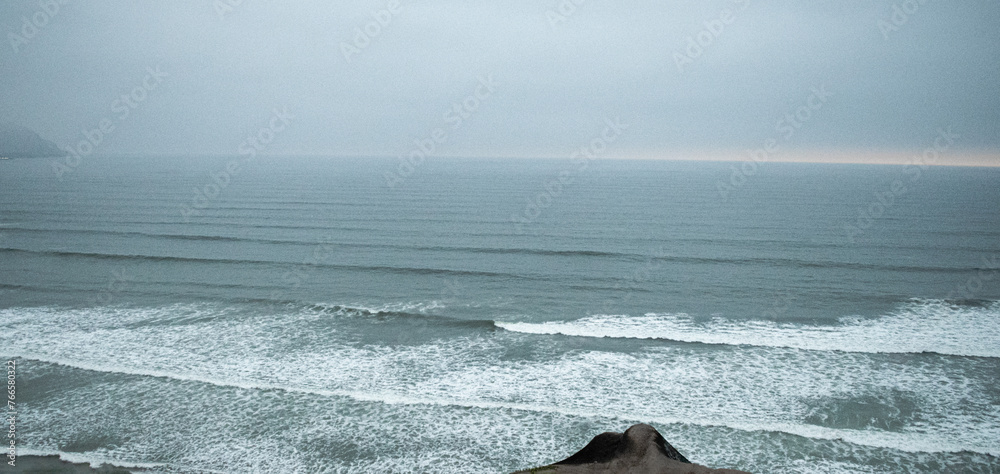 Naklejka premium waves on the beach with a mountain in the blue background