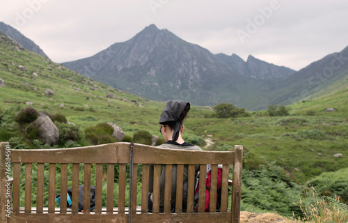 Hiker resting on a bench on the Glen Rosa hiking route on the Isle of Arran, Scotland, UK