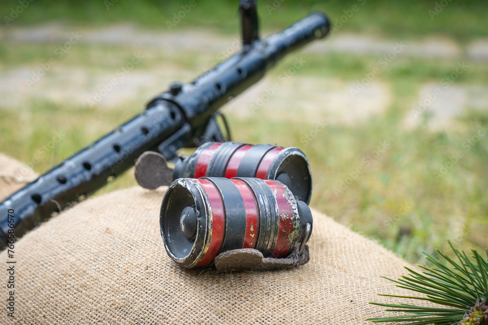 Fototapeta premium WWII machine gun and two black red hand grenades on sandbags