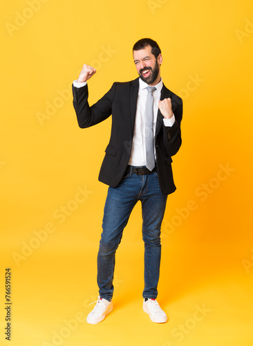 Full-length shot of business man over isolated yellow background celebrating a victory © luismolinero