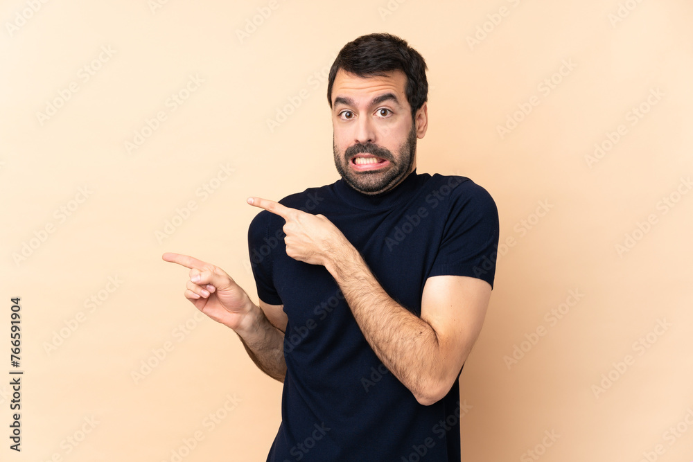 Caucasian handsome man over isolated background frightened and pointing to the side Caucasian handsome man over isolated background frightened and pointing to the side