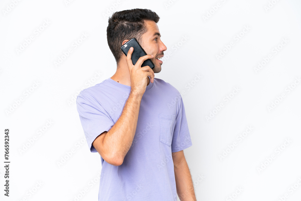 Young handsome man over isolated white background keeping a conversation with the mobile phone with someone Young handsome man over isolated white background keeping a conversation with the mobile phone with someone