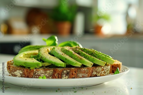 Toasted rye bread with sliced avocado and herbs in plate on table on blurred kitchen background