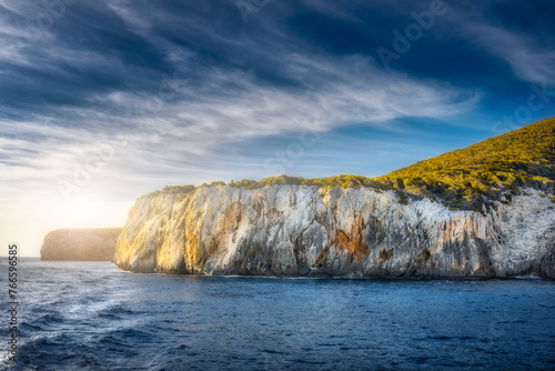 Summer sea landscape of a cliff covered with green trees at sunset on a sunny day