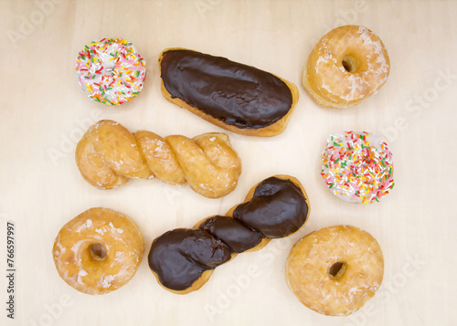 Flat lay top view of variety of donuts. Chocolate and Glazed twists, frosted cake sprinkles with sprinkles and basic glazed donuts © sheilaf2002