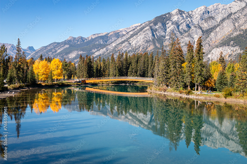 Autumn trees reflect on a river in the mountains