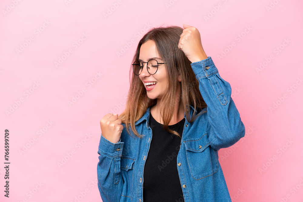 Young caucasian woman isolated on pink background celebrating a victory