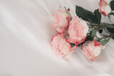 Pink rose flower bouquet on silk fabric beige background.