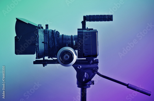 Video camera rig on a tripod, ready for shooting. Professional type of equipment, symbol of filmaking industry and entertainment. Side view, color graded shot